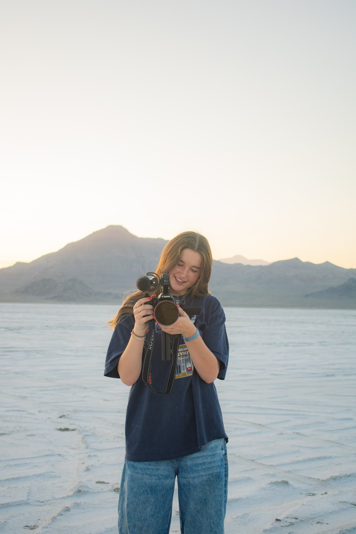 Bailey Nye holding a camera on the salt flats at sunset